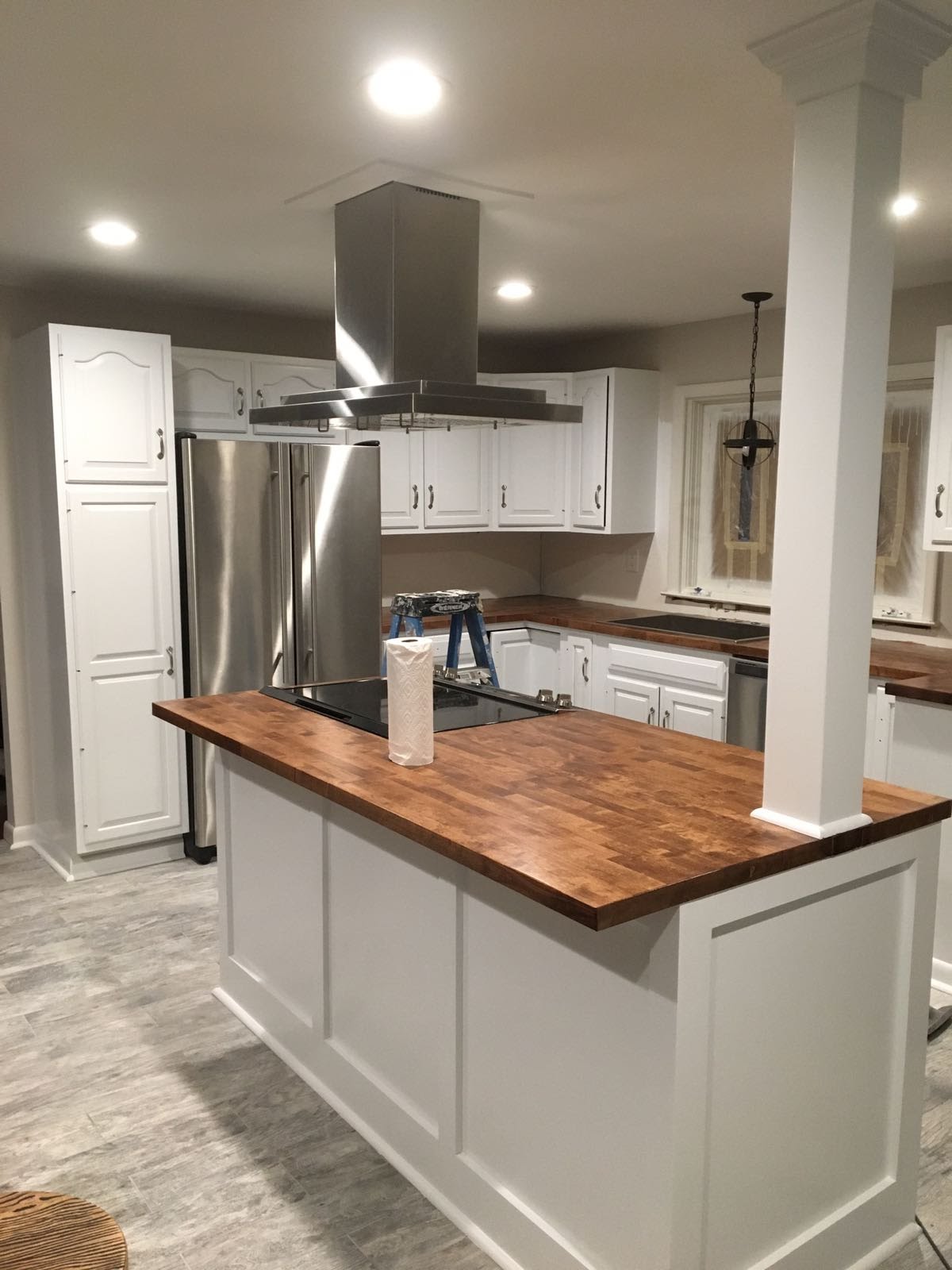 Finished kitchen with white cabinetry, stainless steel range hood and refrigerator, and a butcher-block island by Rome Leite Home Improvement in Danbury, CT