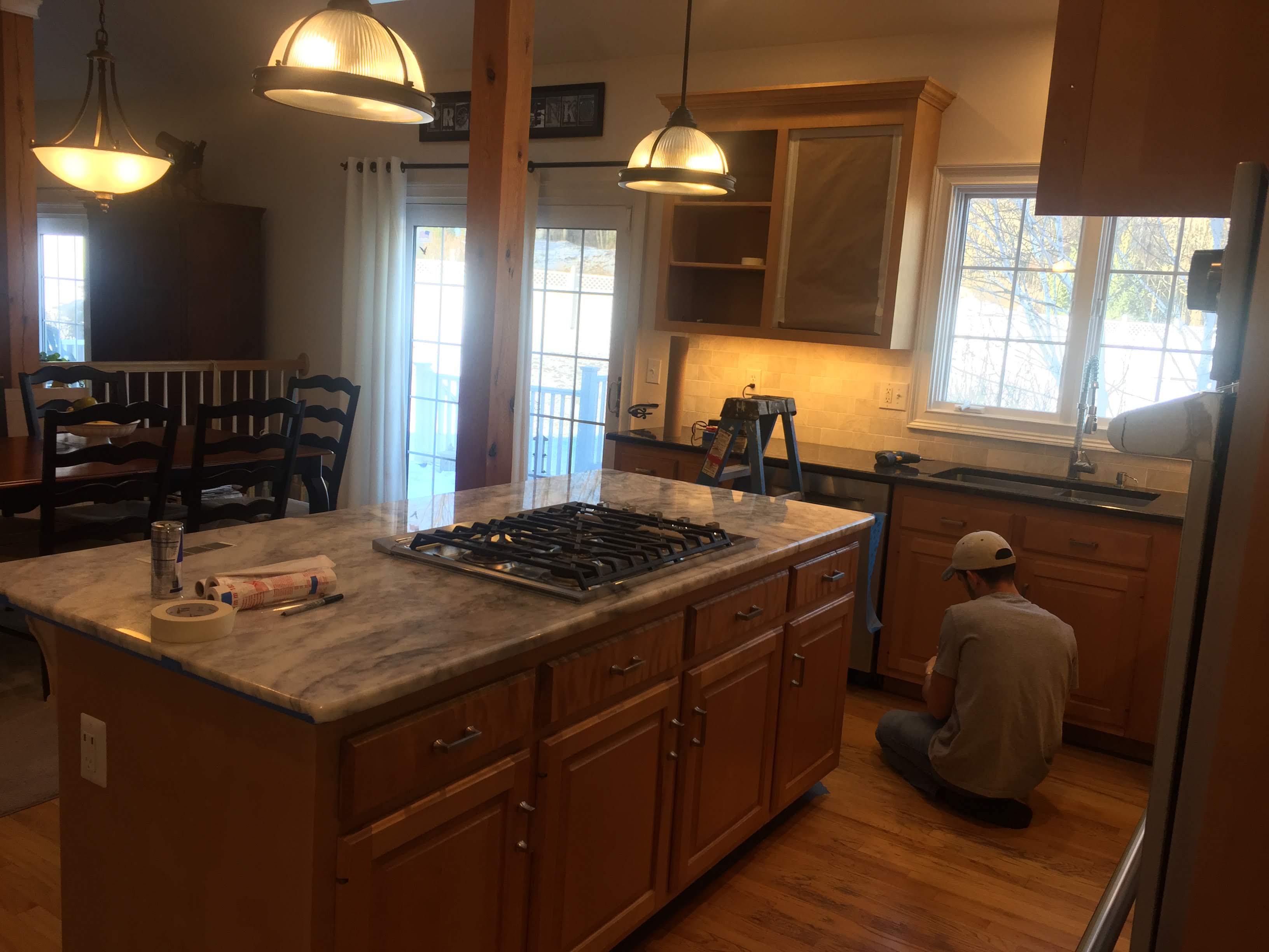 Kitchen island with a marble-look countertop and gas cooktop, wood cabinets, and pendant lighting by Rome Leite Home Improvement in Danbury, CT